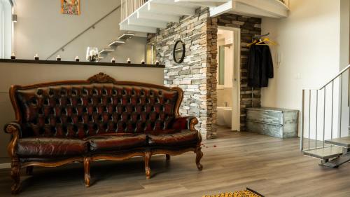 a leather couch in a room with a brick wall at Klimt & Van Gogh Vista Lago by Abitare Il Tempo in Nemi