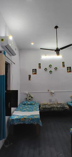 a room with two beds and a ceiling fan at Vardaan Rooms in Prayagraj