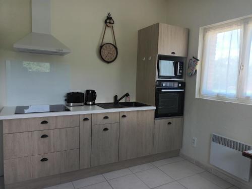 La cuisine est équipée de placards en bois, d'un évier et d'un four micro-ondes. dans l'établissement Aux 40 Écus - Gingko, à Puycornet