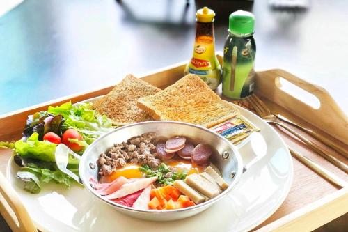 een dienblad met een kom eten, salade en brood bij Phorpun Resort Lampang in Ban Mai