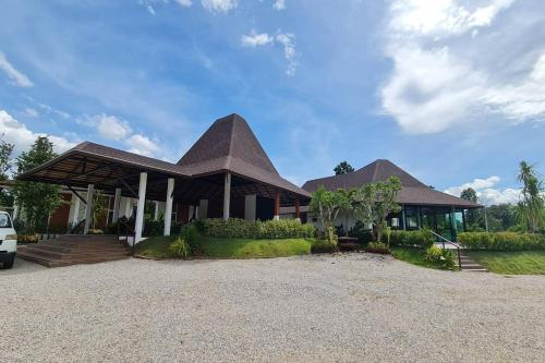 a house with a peaked roof on a gravel driveway at Phorpun Resort Lampang in Ban Mai