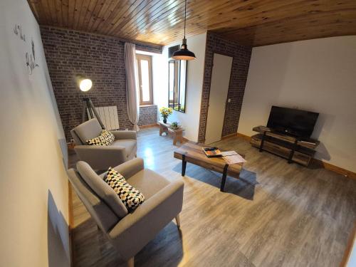 - un salon avec deux chaises et une télévision à écran plat dans l'établissement Au Pied des Remparts, à Villeneuve