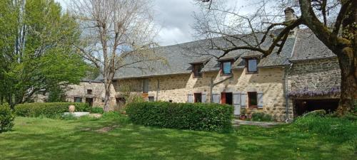 une grande maison en pierre avec une cour herbeuse dans l'établissement Chambre d'hôte, à Meymac