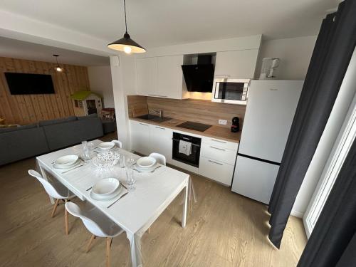 - une cuisine avec une table et des chaises blanches dans la chambre dans l'établissement La Jonquille, Appartement Centre Ville de Gérardmer, linge et ménage inclus, à Gérardmer