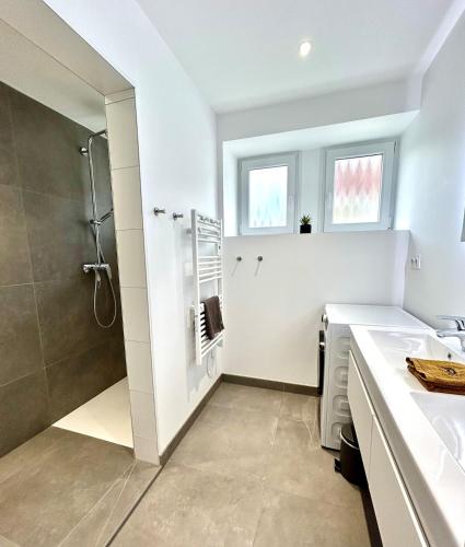 une salle de bain blanche avec une douche et un lavabo dans l'établissement La Jonquille, Appartement Centre Ville de Gérardmer, linge et ménage inclus, à Gérardmer