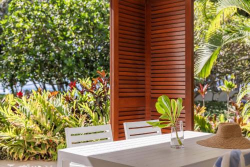 a table with two chairs and a vase on it at Mantra Amphora in Palm Cove