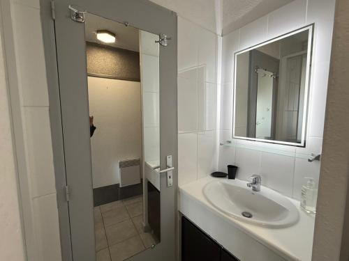 une salle de bain blanche avec un lavabo et un miroir dans l'établissement Beau studio sur coursives à Port Nature au village naturiste, au Cap d'Agde