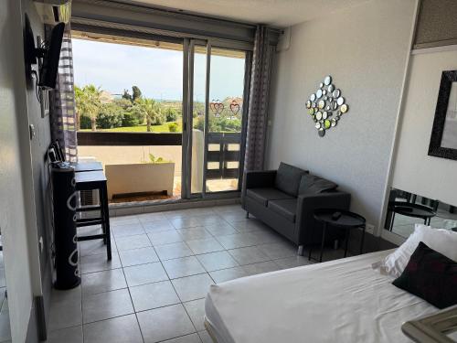 - une chambre avec un lit et un salon avec vue dans l'établissement Beau studio sur coursives à Port Nature au village naturiste, au Cap d'Agde