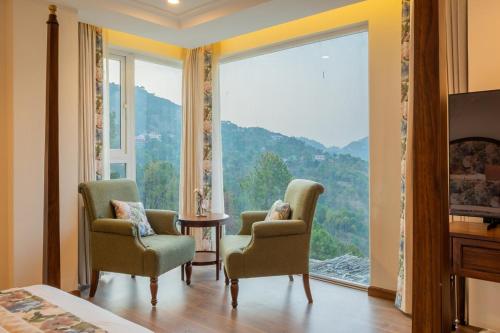una stanza con due sedie e una grande finestra di ELIVAAS privé Royce Cottage Hilltop 4 BHK Retreat With Indoor Bar, Terrace & Scenic Views a Kasauli
