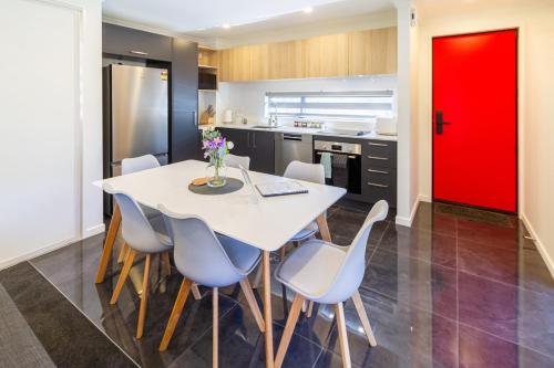 a kitchen with a white table and chairs and a red door at Modern 4BR in Riccarton, Walk to Mall & Park in Christchurch