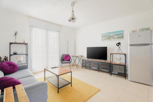 a living room with a couch and a tv at Le Saint Martin Duplexe à la Mer in Bréhal