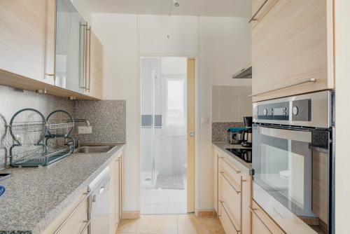 a kitchen with a sink and a stove at Le Saint Martin Duplexe à la Mer in Bréhal