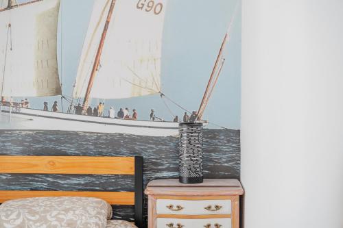 a bedroom with a sail boat on the wall at Le Saint Martin Duplexe à la Mer in Bréhal