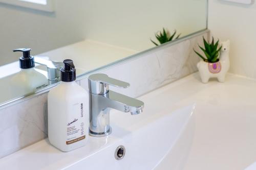 a bathroom sink with a bottle of soap on it at Modern 4BR in Riccarton, Walk to Mall & Park in Christchurch