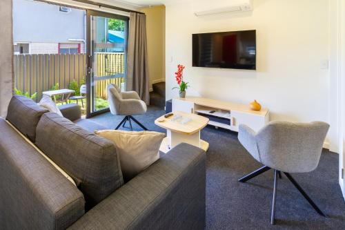 a living room with a couch and a tv at Modern 4BR in Riccarton, Walk to Mall & Park in Christchurch