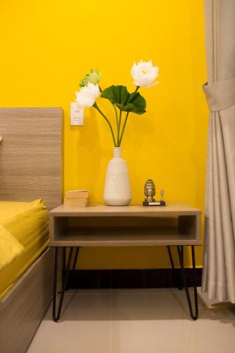 a vase with flowers on a table in a room at Na Homestay in Hue