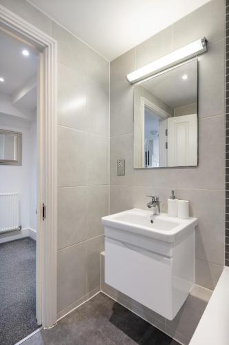 a bathroom with a white sink and a mirror at Stylish 2BR APT with Garden by St Pancras International in London