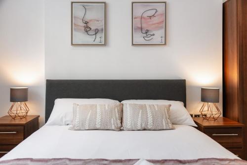 a bedroom with a white bed with three pictures on the wall at Stylish 2BR APT with Garden by St Pancras International in London