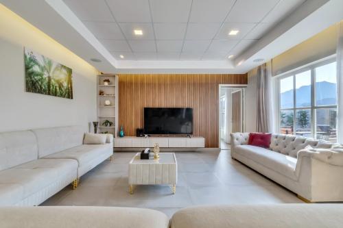 uma sala de estar com mobiliário branco e uma televisão de ecrã plano em 800 Mountain Resort Vacation House em Fujairah
