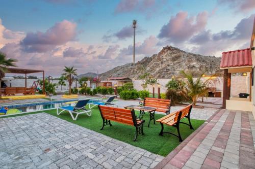 a patio with benches and a table and a pool at Farm Retreat with Pool BBQ Masafi Fujairah in Fujairah