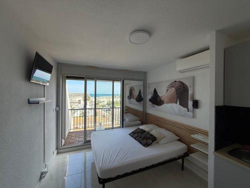 une chambre avec un lit et une grande fenêtre dans l'établissement Studio vue mer avec parking Héliopolis village naturiste, au Cap d'Agde