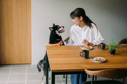 a woman sitting at a table with a dog at 山座熊川 Sanza-Kumagawa in Wakasa