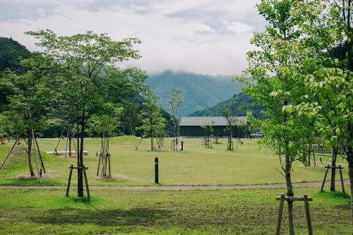 a field with trees and a building in the background at 山座熊川 Sanza-Kumagawa in Wakasa