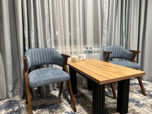 two chairs and a wooden table in a room with curtains at Safia Guest House in Andijan