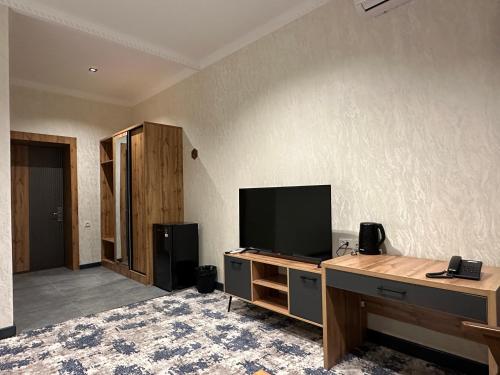 a living room with a tv and a desk with a computer at Safia Guest House in Andijan