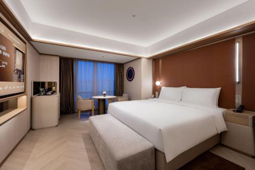 a hotel room with a large bed and a table at Orange Crystal Hotel MixC Shantou East Coast in Shantou