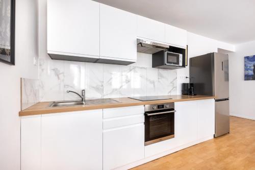 une cuisine blanche avec un évier et un micro-ondes dans l'établissement L'hirondelle, 4 p, à Tourcoing