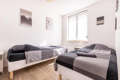 deux lits dans une chambre aux murs blancs dans l'établissement L'hirondelle, 4 p, à Tourcoing