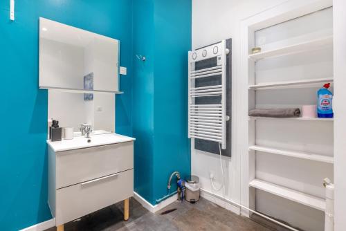 La salle de bains est pourvue d'un lavabo blanc et d'un mur bleu. dans l'établissement L'hirondelle, 4 p, à Tourcoing