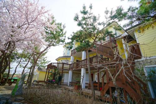 a yellow house with a balcony and trees at Buan bada yeohang pension in Buan