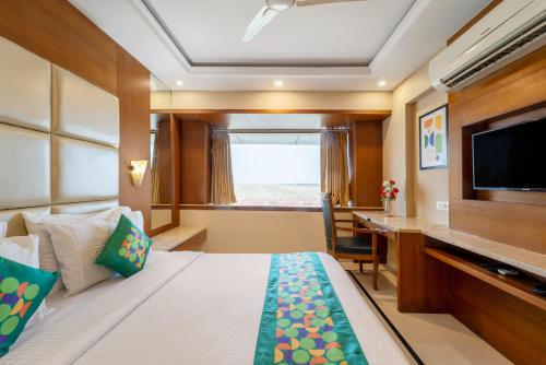 a hotel room with a bed and a desk and a television at Treebo Premium Vinnie - Near Airport in Jaipur