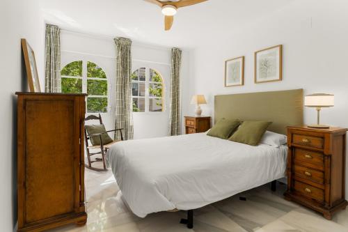 a bedroom with a bed and a dresser and two windows at Piso Vacaciones En Fuengirola in Fuengirola