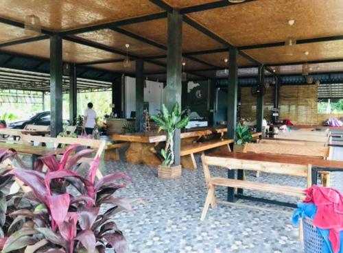 a restaurant with wooden tables and potted plants at มาตาบุรี ริเวอร์เเควรีสอร์ท in Ban Gaeng Cho