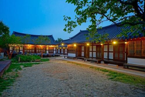 全州市にあるJeonju Hanok Maeul Dongrakwon Hanok Hotelの夜間のベンチ付きの建物