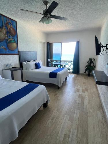 a hotel room with two beds and a balcony at Cancun plaza frente al mar in Cancún
