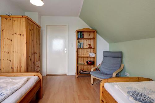 a bedroom with two beds and a blue chair at Gästehaus Tadenswarf in Tadenswarf
