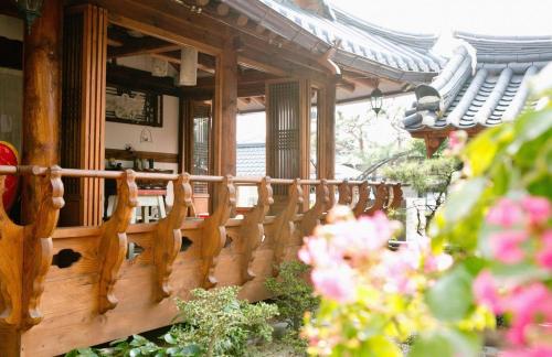 Una barandilla de madera en un porche con flores. en Jeonju Hanok Ihwa Gotaek Banchayougi Josik, en Jeonju