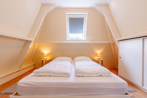 a large white bed in a room with a window at Daisy-Rose aan de Jan Tooropstraat in Domburg