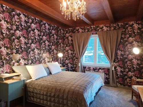 a bedroom with a bed and floral wallpaper at Villa Metsänvartija in Vihtijärvi