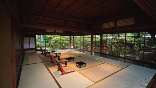 an empty room with chairs and tables and windows at KAWAZU Gastronomy & Traditional Inn in Mashizume