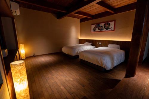 a hotel room with two beds and a lamp at KAWAZU Gastronomy & Traditional Inn in Mashizume