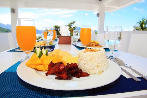 a plate of food on a table with glasses of orange juice at Coron Bluewave Hotel in Coron