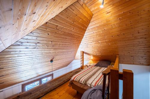 ein Schlafzimmer im Dachgeschoss mit einem Bett in einer Holzdecke in der Unterkunft La Maison Marie Andre in Albens
