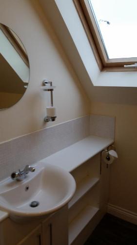 een badkamer met een wastafel en een dakraam bij Livingston Ideal commuter House in Livingston