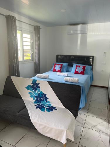 a bedroom with a bed with blue and red pillows at Fare Heana- Beau bungalow Moorea in Moorea