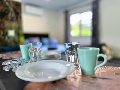 a wooden table with a plate and glasses on it at Fare Heana- Beau bungalow Moorea in Moorea